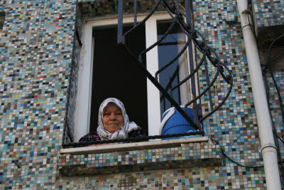 Turkish lady in the window of a tiled house