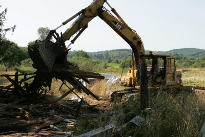 Excavator cleaning up fallen old barn
